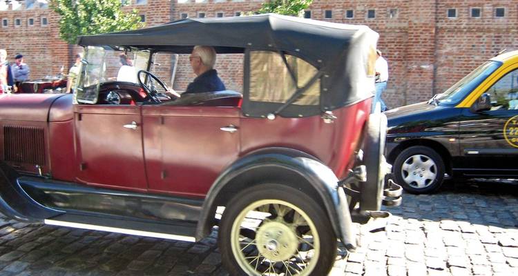Vintage car with passengers in a city setting.