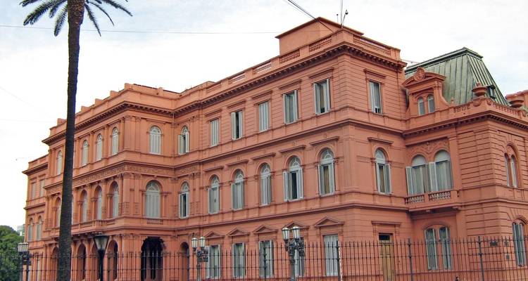 Large historic pink building with palm trees.
