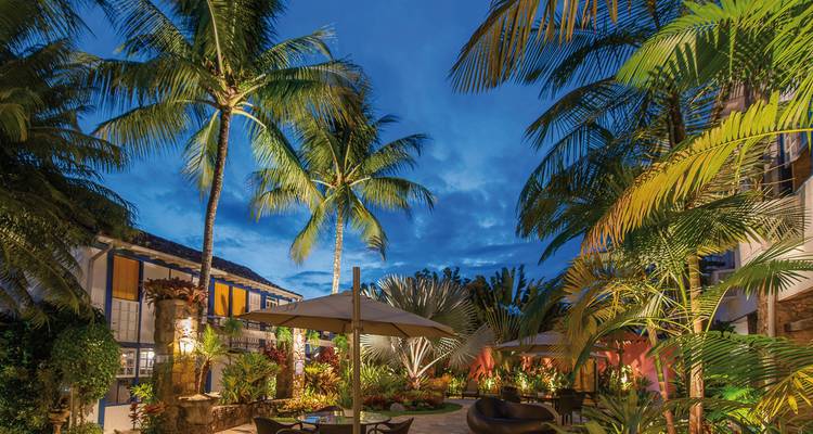 Cour d'hôtel avec palmiers et ambiance du soir.