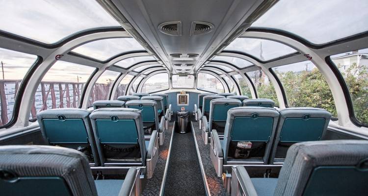 Innenansicht eines Panorama-Zugwaggons mit leeren Sitzen.