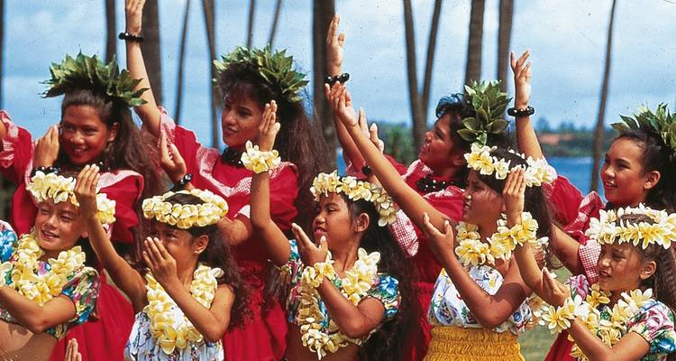 Groep vrouwen in traditionele Hawaiiaanse klederdracht die een dans uitvoeren.