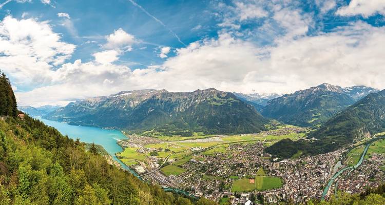 Luchtfoto van een stad omgeven door bergen en een meer.