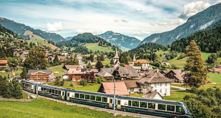 Een schilderachtig bergdorpje met een trein die erdoorheen rijdt.