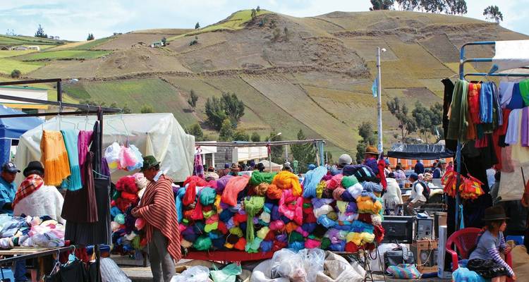 Kleurrijke markt met lokale mensen en textiel op de voorgrond.