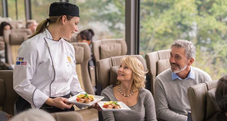 Service de train avec chef et passagers engagés dans le repas.