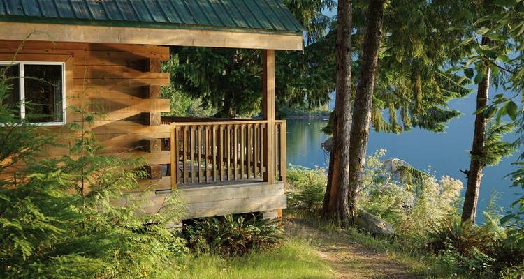 A cozy cabin in a forested area near a lake.