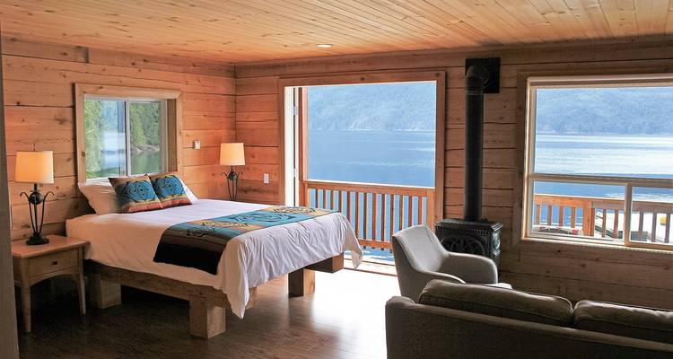 Interior of a cabin room with a bed facing a lake view.