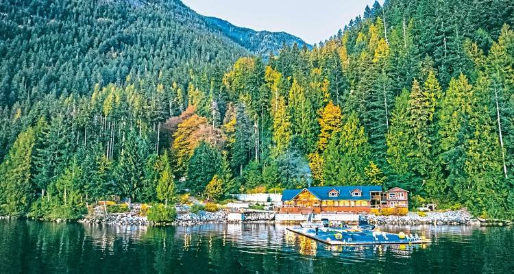A remote lodge situated in a lush forested area by a lake.