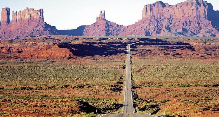 Monument Valley avec une longue route menant vers les formations rocheuses.