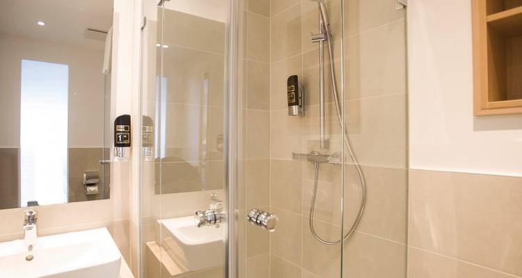 Moderne badkamer met een douche, wastafel en spiegels.
