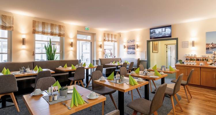 Interieur van een eetgedeelte met gedekte tafels voor een maaltijd.