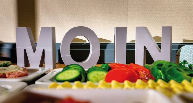 Voedselpresentatie met groenten en het woord MOIN uitgespeld in blokletters.