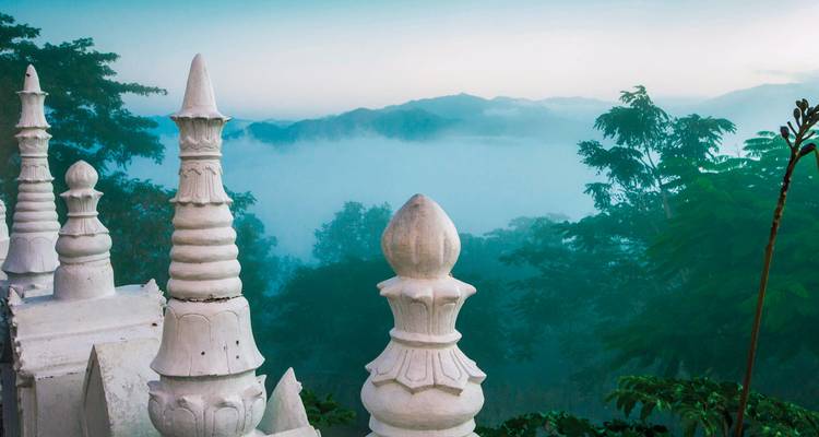 Sierlijke witte pagode tegen een mistige bosachtergrond.