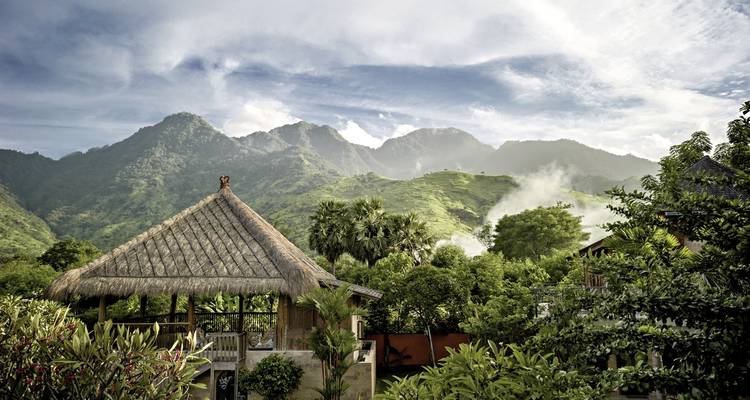 Pabellón tropical enclavado en un paisaje exuberante con montañas.
