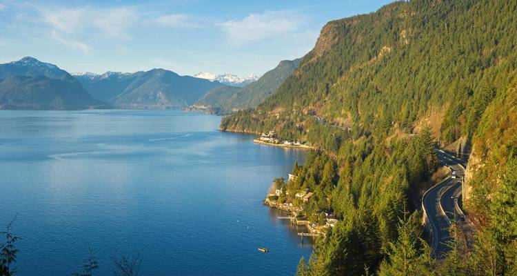 Vista costera panorámica del Howe Sound con laderas boscosas y la sinuosa carretera Sea-to-Sky Highway.