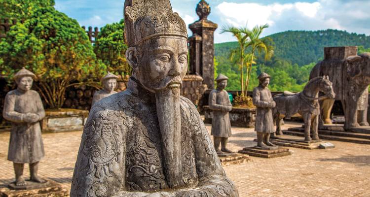 Standbeelden van krijgers op een historische locatie met groen eromheen.