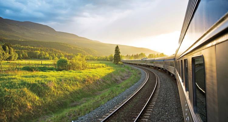 Voyage en train à travers des paysages verdoyants illuminés par le coucher de soleil.