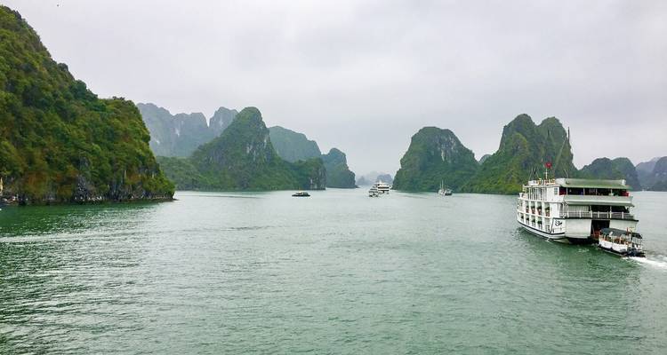 Halong Bucht's Kalksteininseln mit Booten auf ruhigen Gewässern.