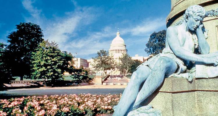 Le dôme du Capitole américain s'élève derrière des jardins et une statue allongée par une journée ensoleillée à Washington, D.C.