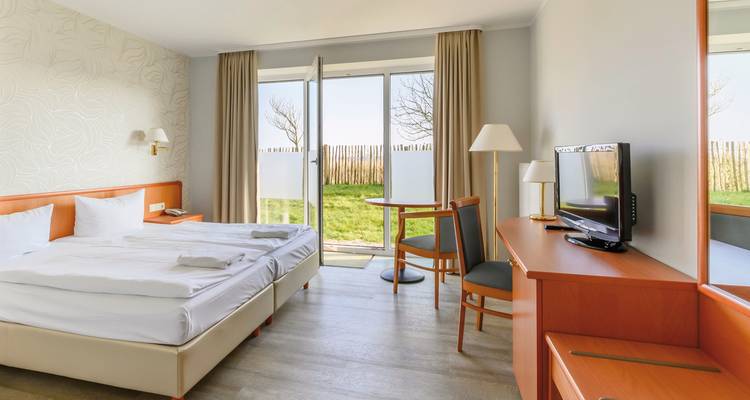 Hotelzimmer-Innenraum mit Doppelbett und Blick auf den Garten.