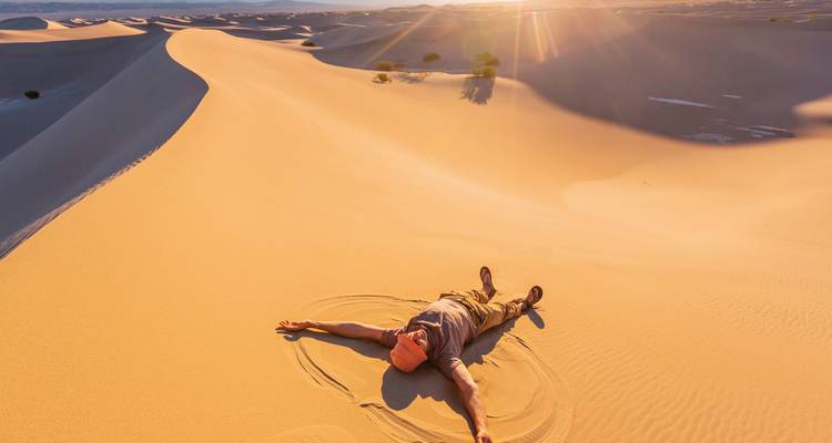 Personne allongée sur des dunes de sable se prélassant au soleil.