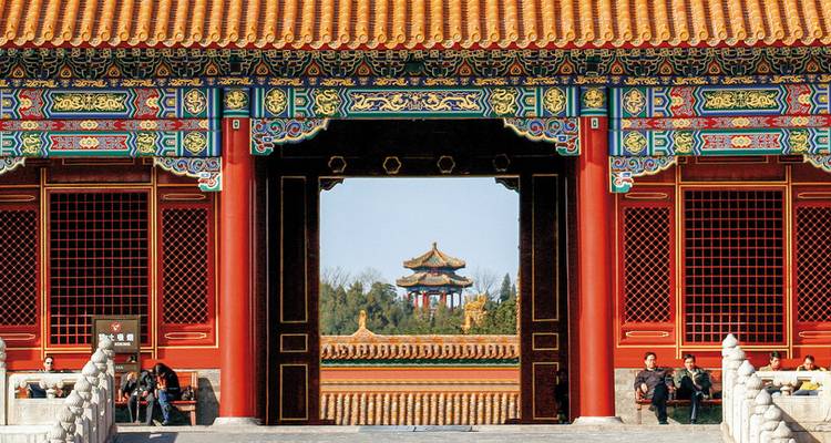 Zicht op een ingang van traditionele Chinese architectuur met wandelende mensen.