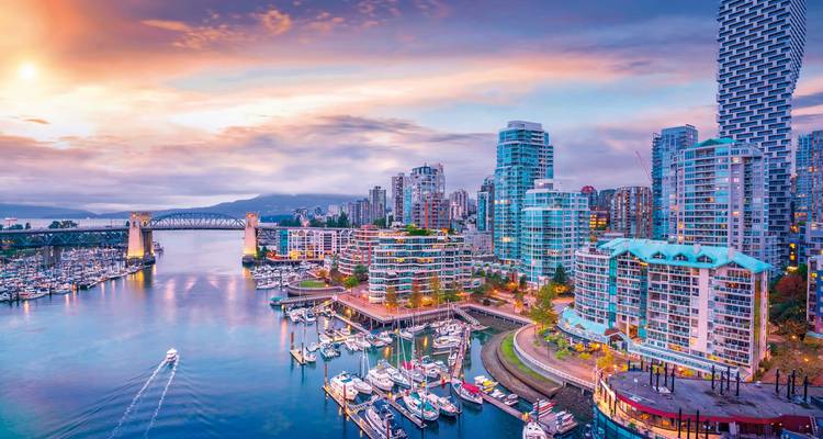 A cityscape with colorful buildings and a bridge at sunset.