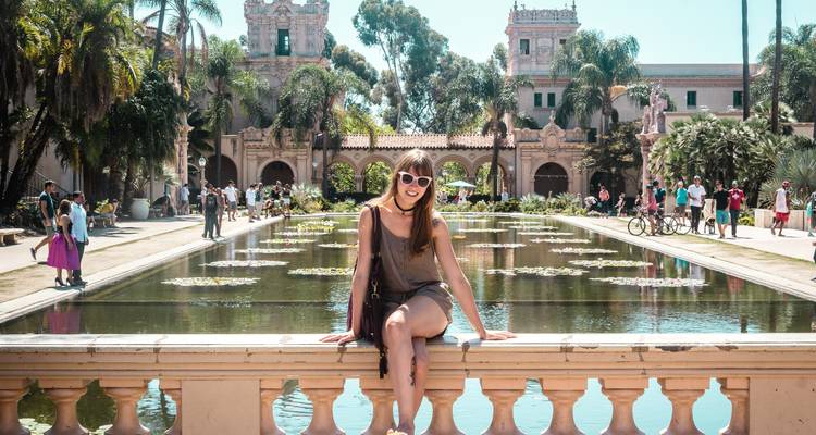 Una persona sentada junto a un estanque reflectante en un jardín histórico.