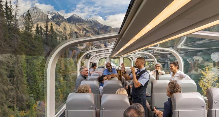 Touristes à l'intérieur d'un train avec une vue panoramique sur les montagnes.