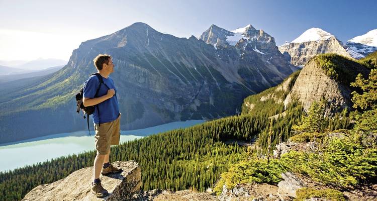 Randonneur avec un sac à dos contemplant un paysage de montagne.
