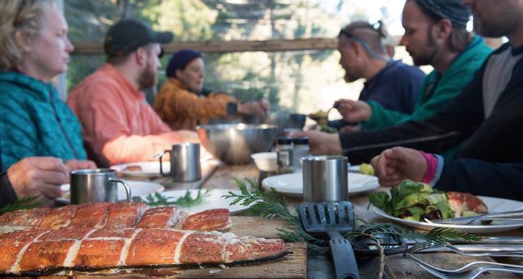 Groep mensen die genieten van een maaltijd met gegrilde zalm.