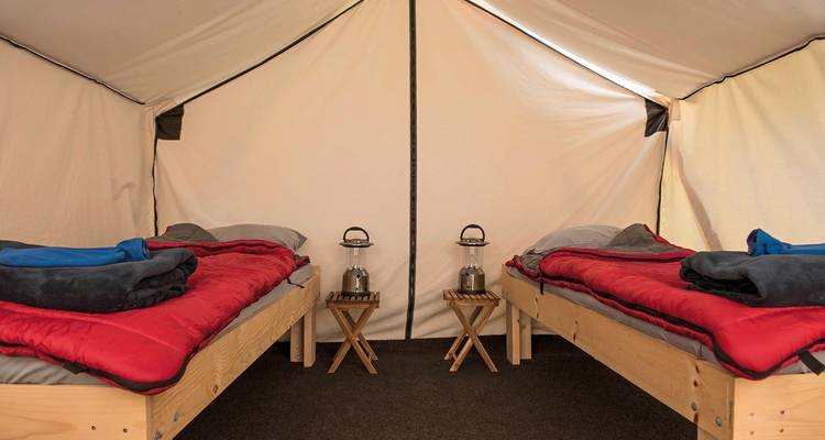 Interieur van een gezellige tent met twee eenpersoonsbedden opgesteld voor kamperen.