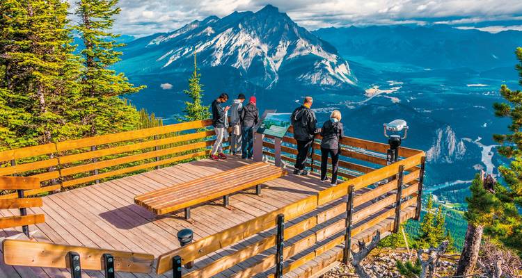Wooden observation deck with people looking at a mountain landscape.