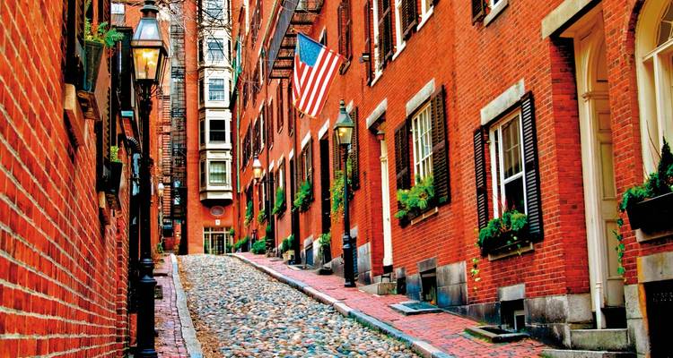Historic red-brick street with an American flag and old-style lamps.