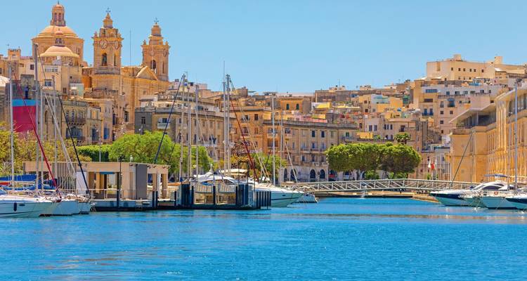 Marina mit Yachten und historischen Gebäuden am Wasser.