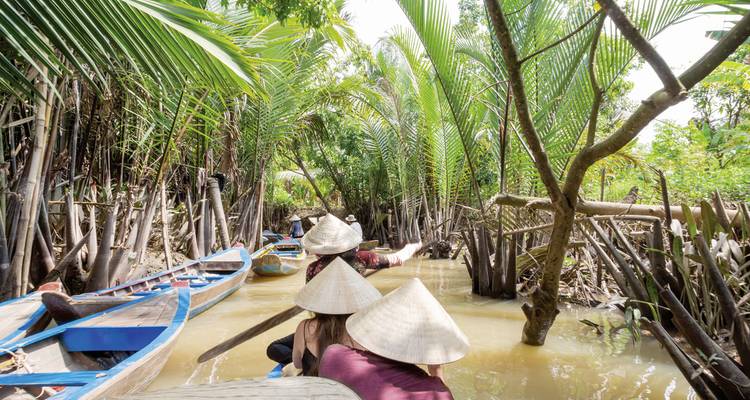 Des personnes voyageant en bateau à travers des mangroves luxuriantes.