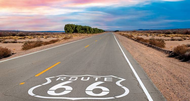 A long stretch of a deserted highway with the iconic Route 66 emblem painted on the road.