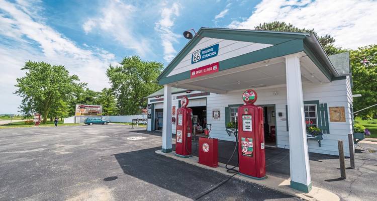 A classic gas station with vintage fuel pumps and a Route 66 sign.
