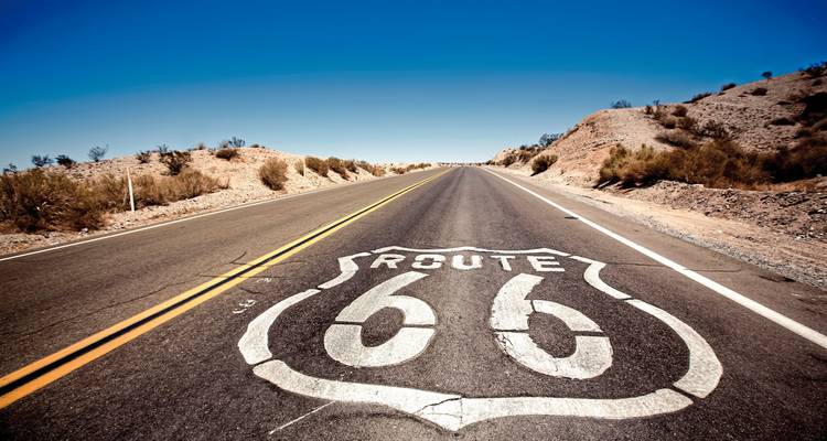 Route 66 gemarkeerde weg die zich uitstrekt naar de horizon in een woestijnlandschap.