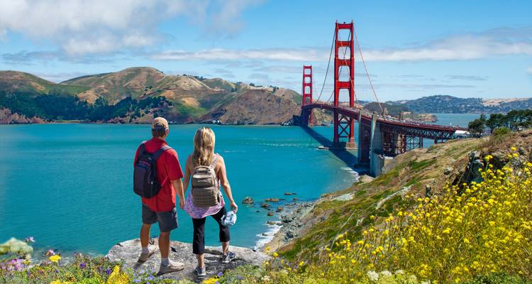 Couple enjoying the view of a famous red bridge over a bay.