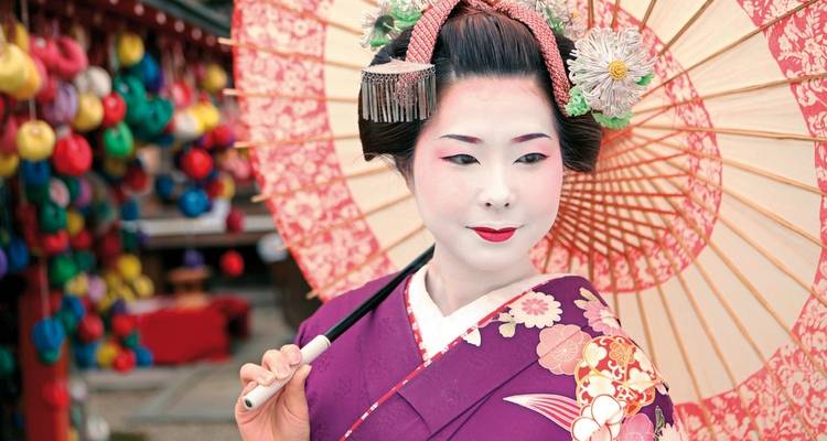 Geisha in traditionele kledij met een parasol en levendige achtergrond van kleurrijke decoraties.