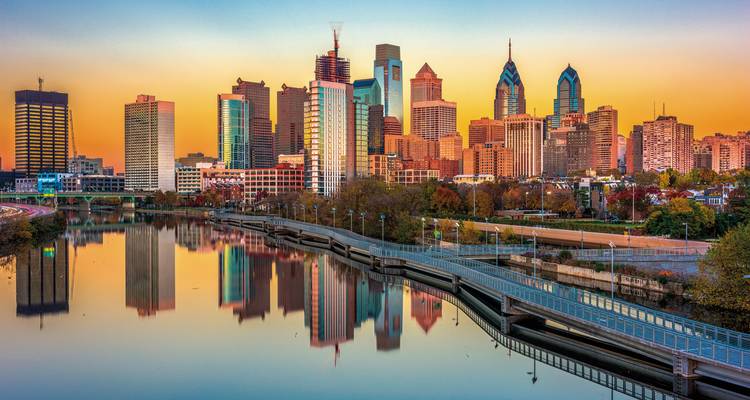 Philadelphia skyline with reflective river at sunset.