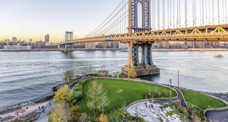 Manhattan Bridge en park met mensen op het gras.