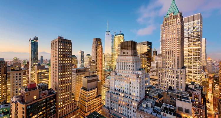 New York City skyline met verlichte gebouwen in de schemering.