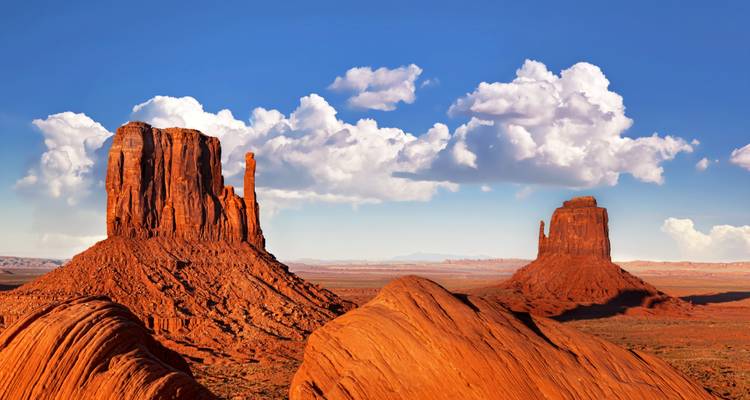 Buttes emblématiques de Monument Valley sous un ciel bleu dégagé.