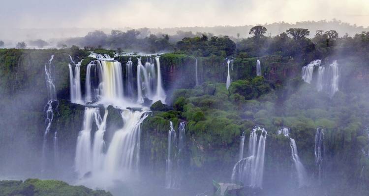 Nebel steigt von den Iguazu-Wasserfällen auf, umgeben von Regenwald.