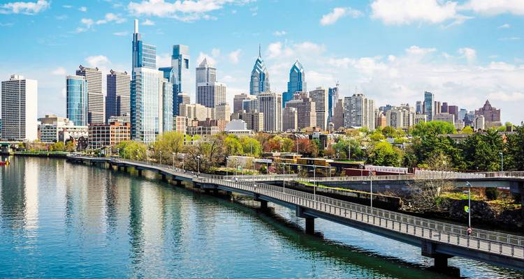 Een stadshorizon die weerkaatst in een rivier onder een heldere hemel.