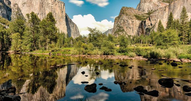 Une scène de rivière sereine entourée de falaises de granit imposantes.