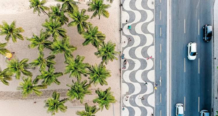 Aerial view of Copacabana beach with palm trees and road.