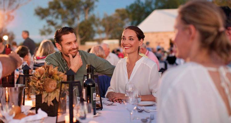 A couple dining outdoors with others around a table.